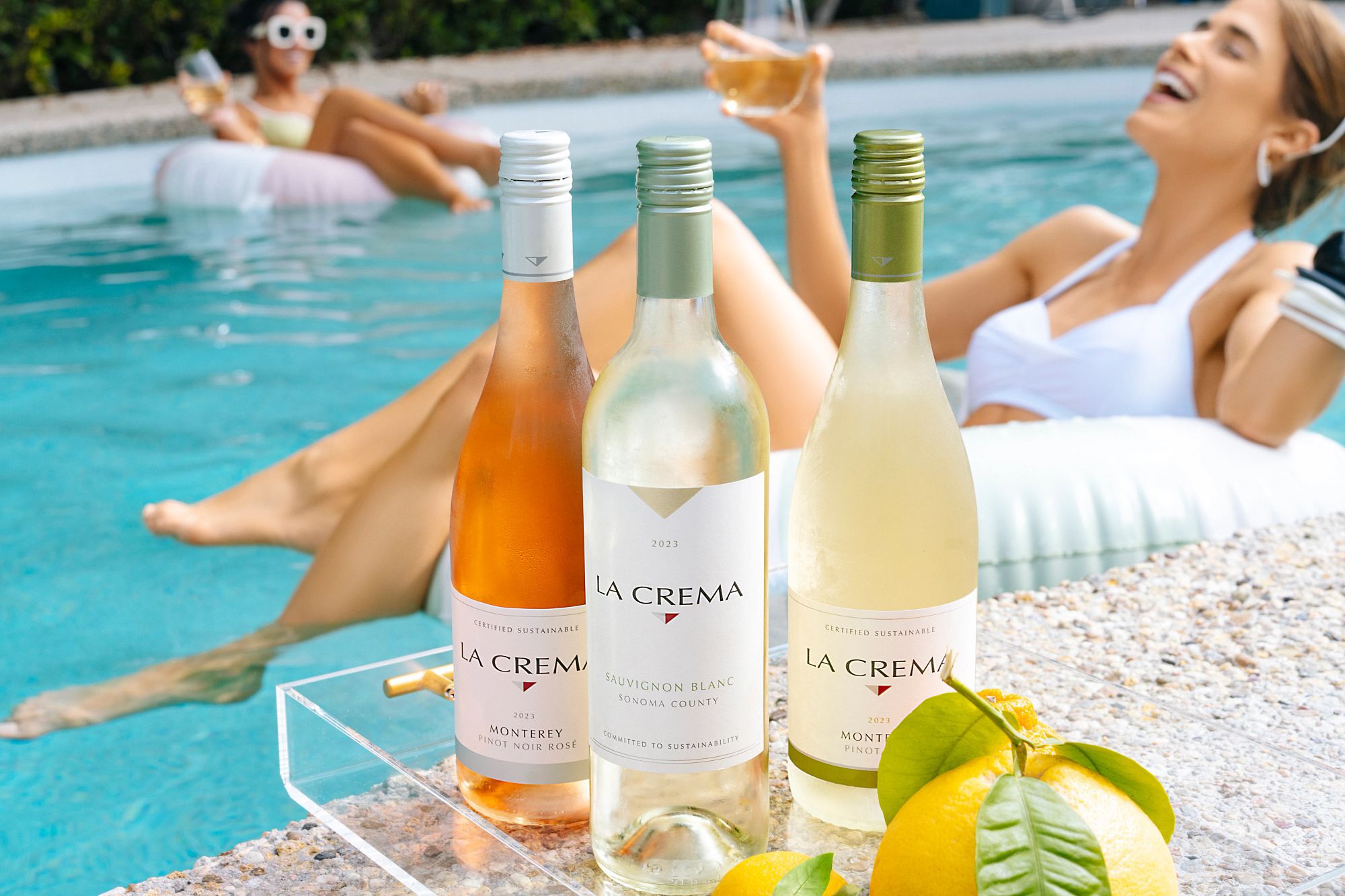 Two friends hanging in a pool enjoying La Crema wine